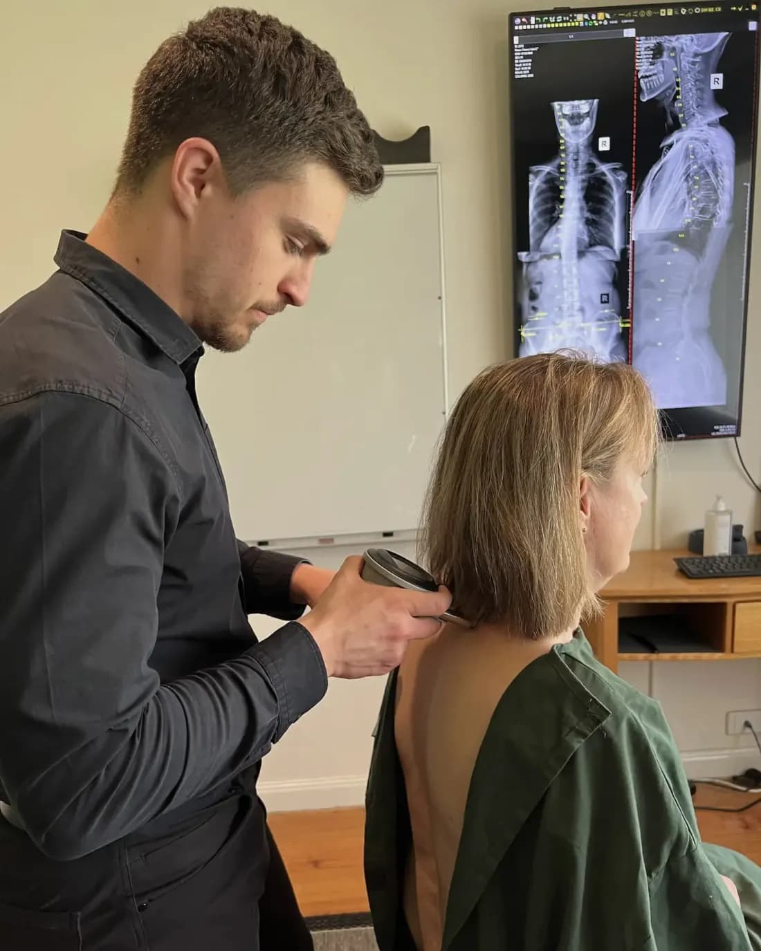 Dr Arthur Kaganovitch using a Gonstead instrument on a patient's neck